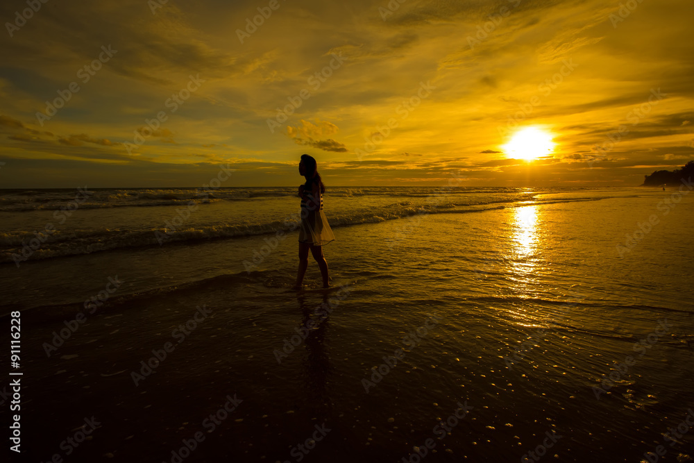 Young woman silhouettes standing on beach at sunset Young woman silhouettes standing on beach at sunset