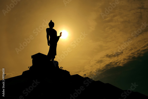 Thai buddha statue over scenic sunset sky background
