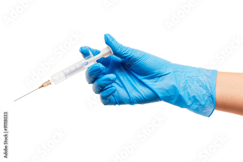 Close up of female doctor's hand in blue sterilized surgical glove with plastic medical syringe against white background