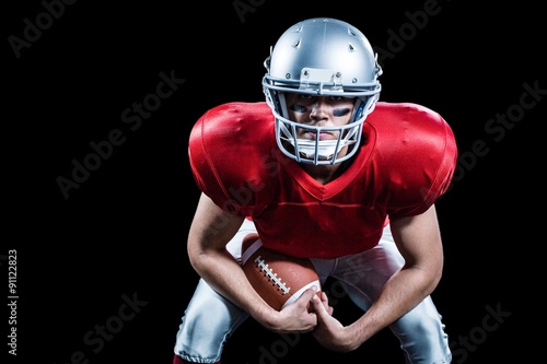 Portrait of American football player bending while holding ball