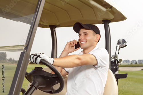 Man sitting in a golf cart and talking on phone