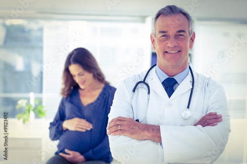 Portrait of male doctor with pregnant woman at clinic