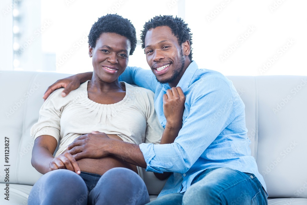 Happy pregnant woman with husband sitting at home Happy pregnant woman with husband sitting at home