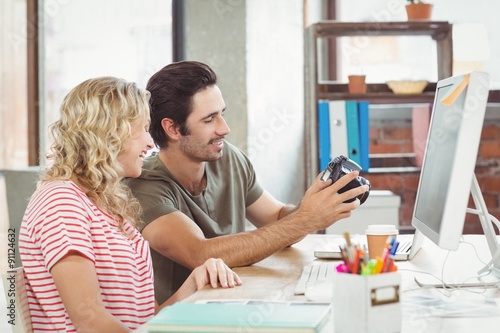 Man and woman looking at digital camera in office