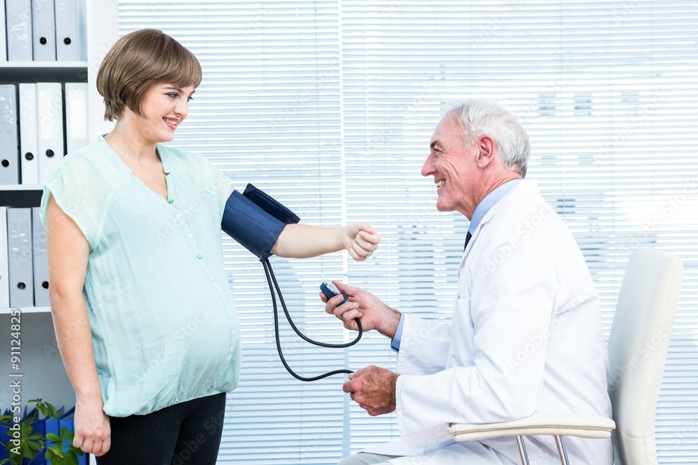 Fototapeta premium Doctor checking blood pressure of pregnant woman