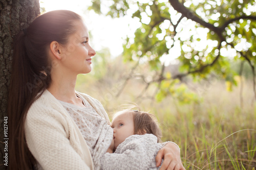 young mother feeding toddler outdoors