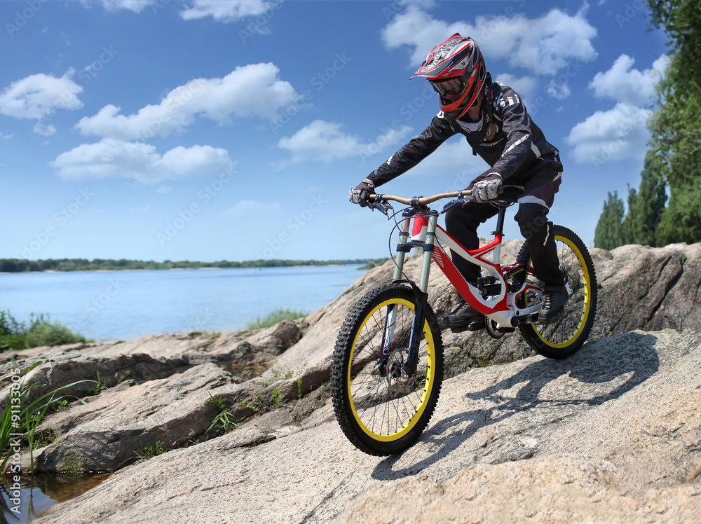 Sportsman in sportswear on a mountain bike rides on the stones in the extreme style of downhill Sportsman in sportswear on a mountain bike rides on the stones in the extreme style of downhill