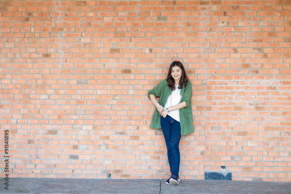 Happy asian woman with black Hair standing Against Old Brick Wal