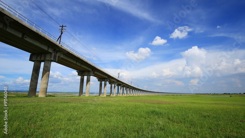 4k Time-lapse of Bridge of railway cross grass field meadow at Pasuk River Dam in summer, Lopburi, Thailand photo