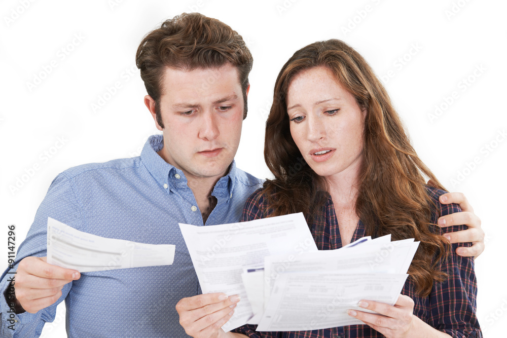 Studio Shot Of Worried Couple Looking At Bills Studio Shot Of Worried Couple Looking At Bills