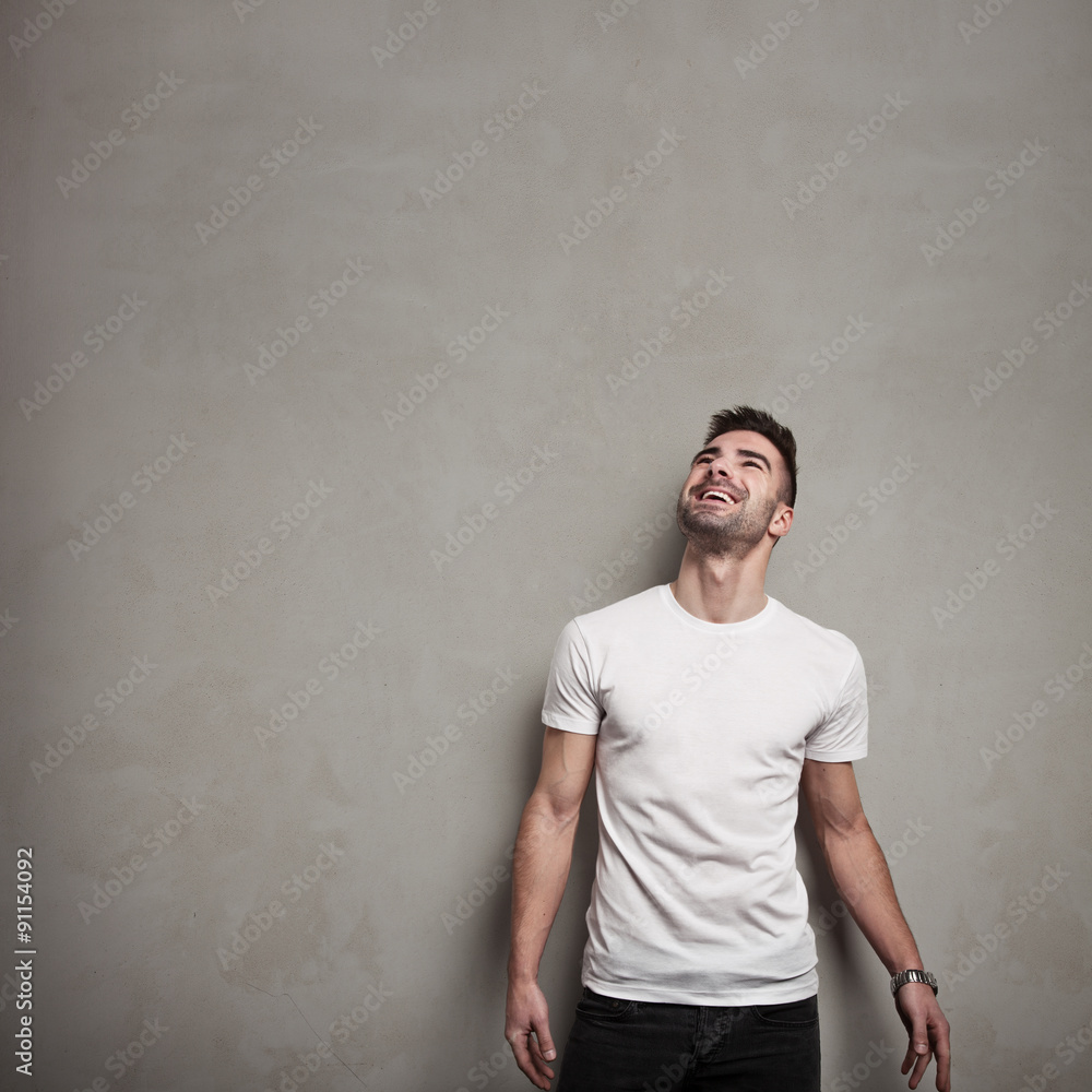 Smiling man in blank t-shirt, grunge concrete wall background Smiling man in blank t-shirt, grunge concrete wall background