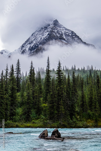 Mt Robson peeks through clouds over Robson River in Robson Provi