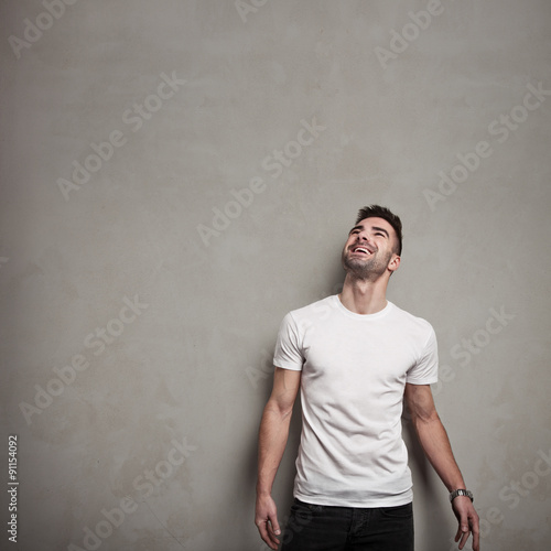 Smiling man in blank t-shirt, grunge concrete wall background
