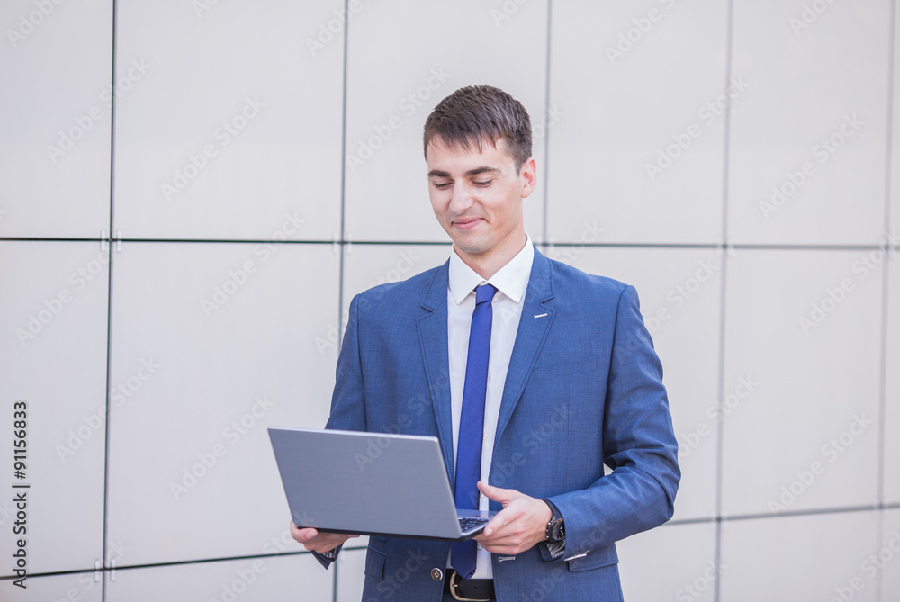 Successful businessman standing in the street holding a laptop Successful businessman standing in the street holding a laptop