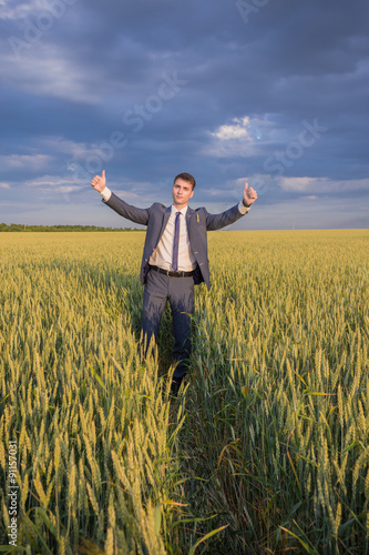 happy farmer  businessman  standing in wheat field with his