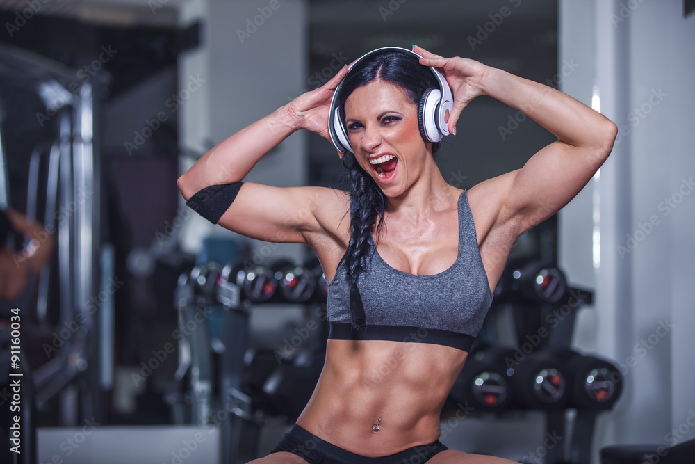 Foto Stock Crazy fit girl posing in gym with headphone. | Adobe Stock
