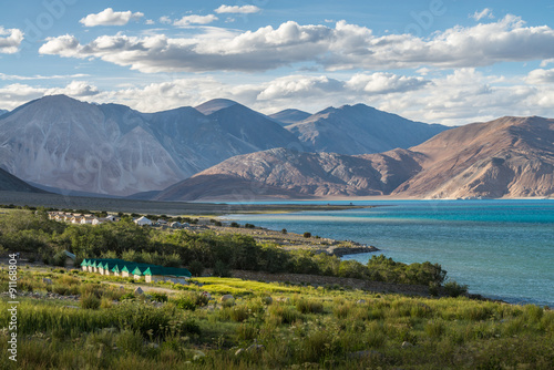 Beautiful green field view at Pangong lake with some tents for tourist and mountain range background