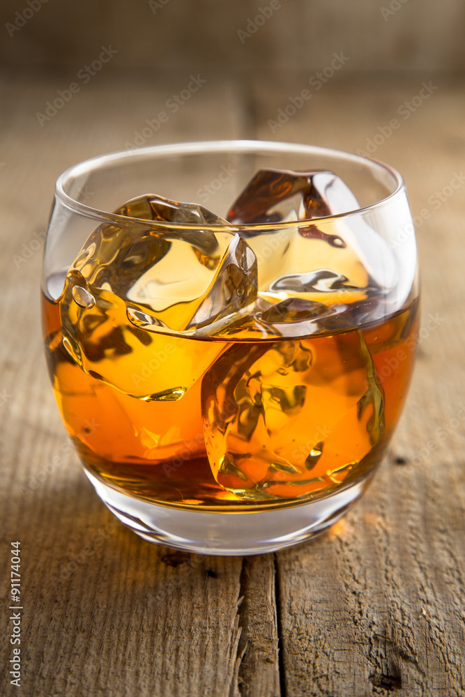 Vertical shot of lone glass of whisky bourbon on the rocks ice vintage  reclaimed wood Stock Photo