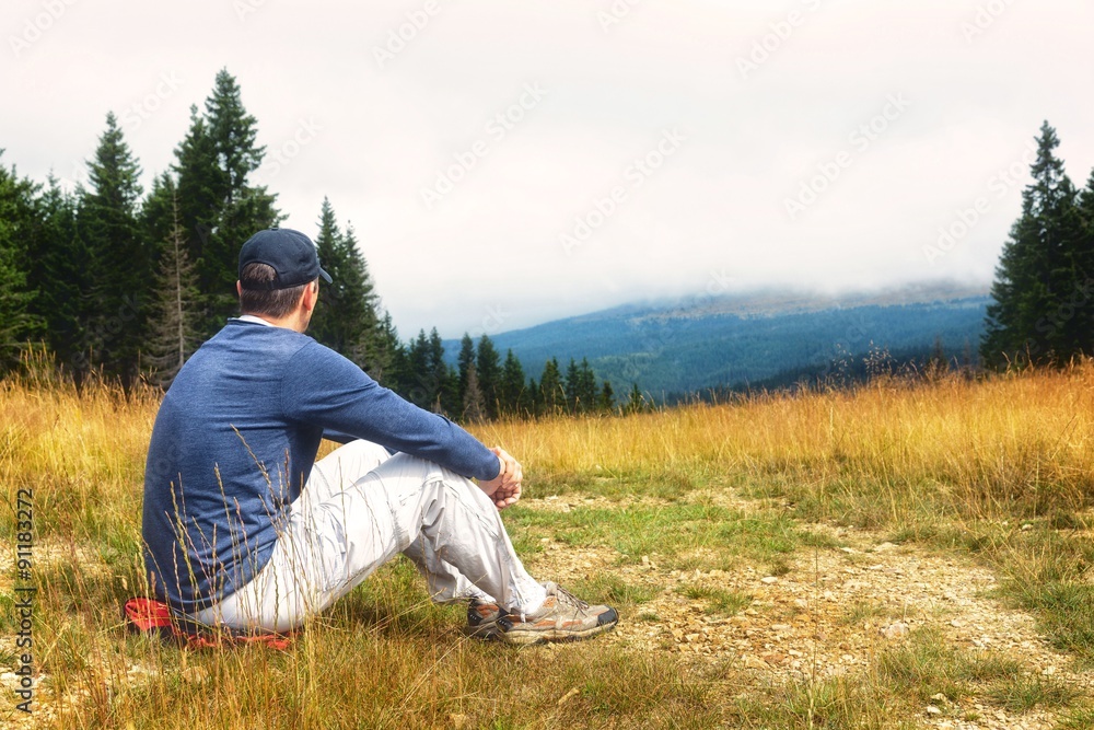 Seated young man,enjoying a mountain view. Seated young man,enjoying a mountain view.