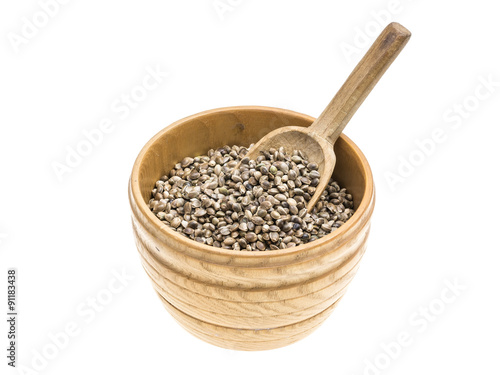 Wooden bowl with hemp seeds and wood spoon on white background