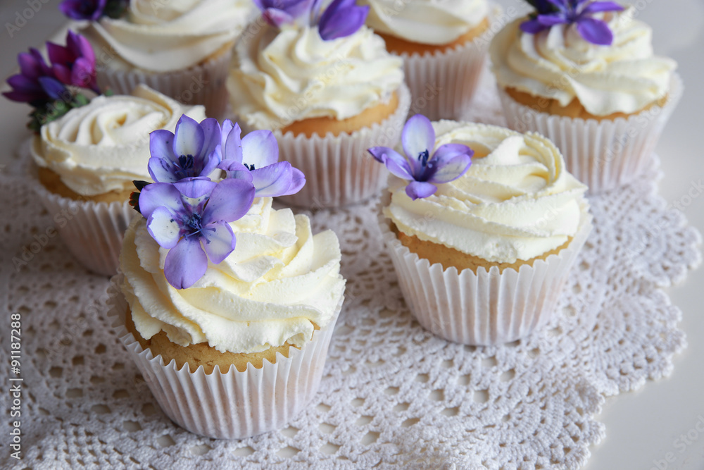 Homemade purple freesia flowers on vanilla cupcakes with whipped Homemade purple freesia flowers on vanilla cupcakes with whipped