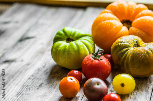Colorful heirloom tomatoes on rustic wooden background photo