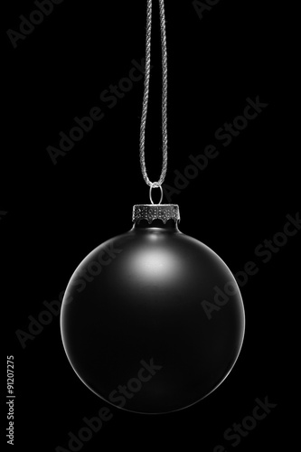 Hanging black Christmas ornament on a black background. Low key.