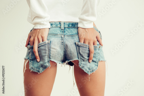 beautiful sexy young woman in  mini jeans shorts shows an obscen