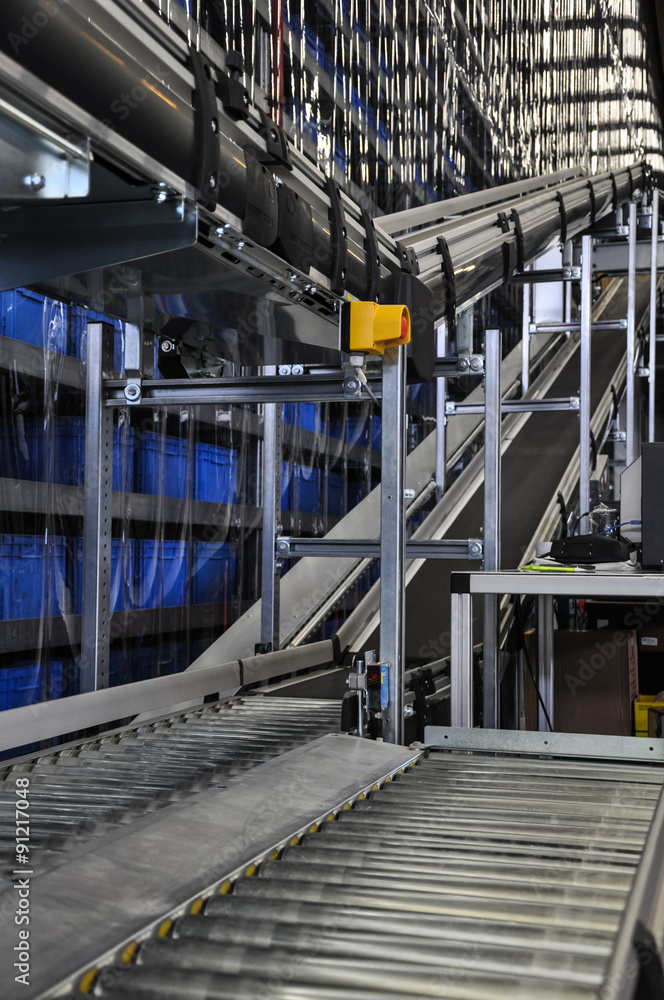 Close up shot of two roller conveyors in an automated warehouse with an emergency stop button.