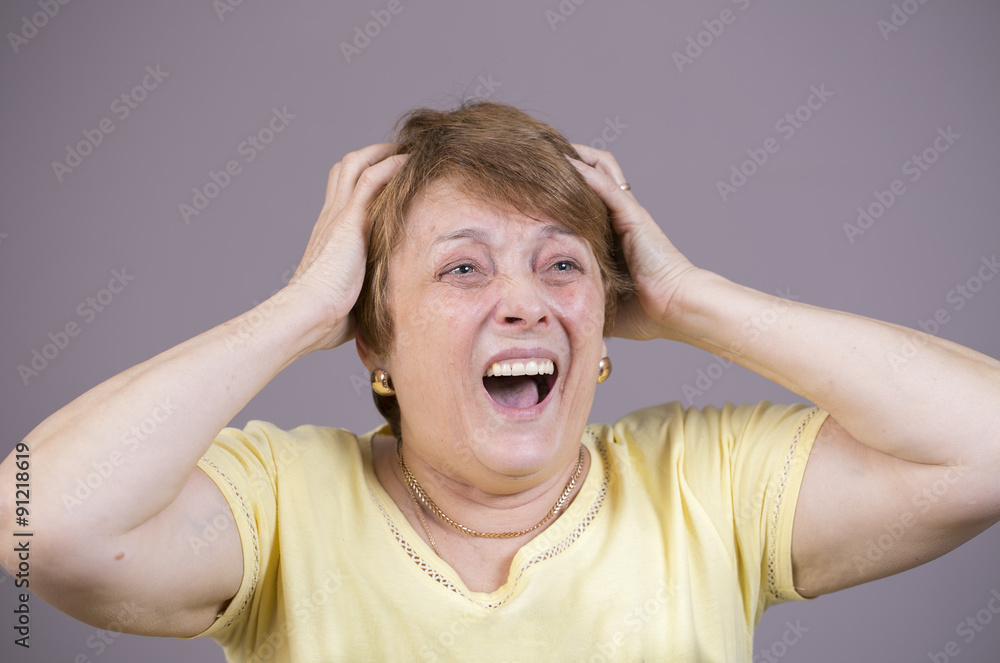 Very emotional woman screams in grief on a gray background. Very emotional woman screams in grief on a gray background.