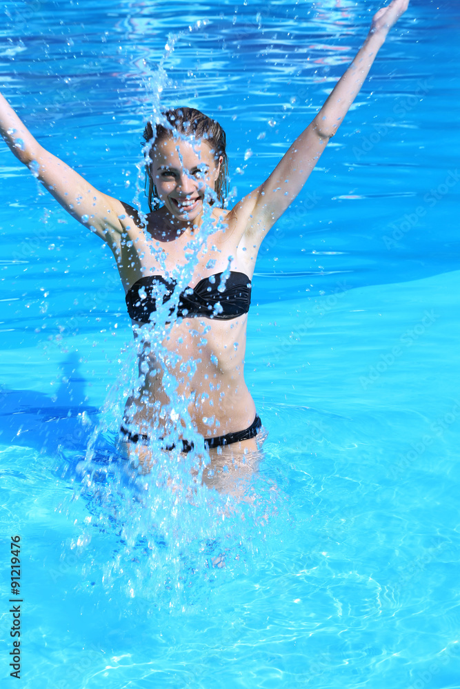 Young woman enjoying in swimming pool at summertime