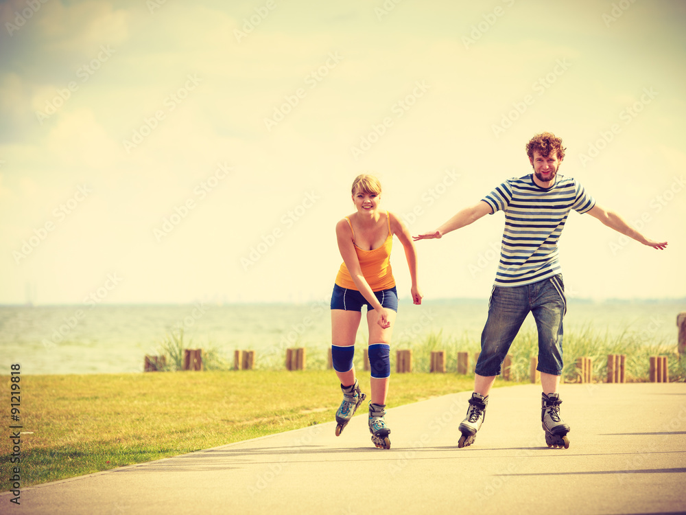 Obraz premium Young couple on roller skates riding outdoors