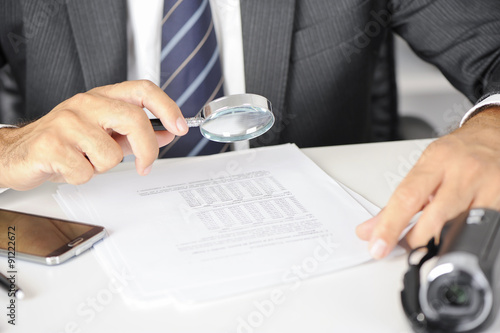 Canvastavla Businessman with magnifying glass reading documents