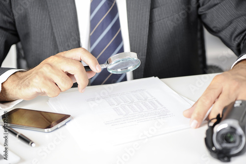 Cuadro en lienzo Businessman with magnifying glass reading documents