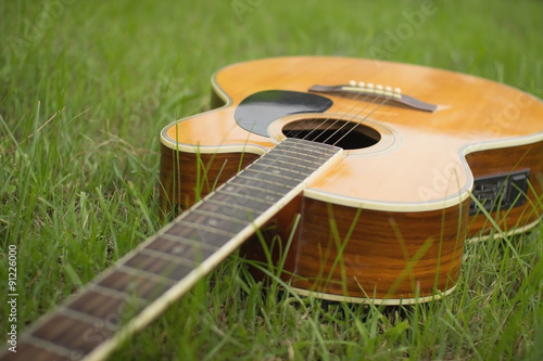 Acoustic guitar on grass with vintage tone and soft focus