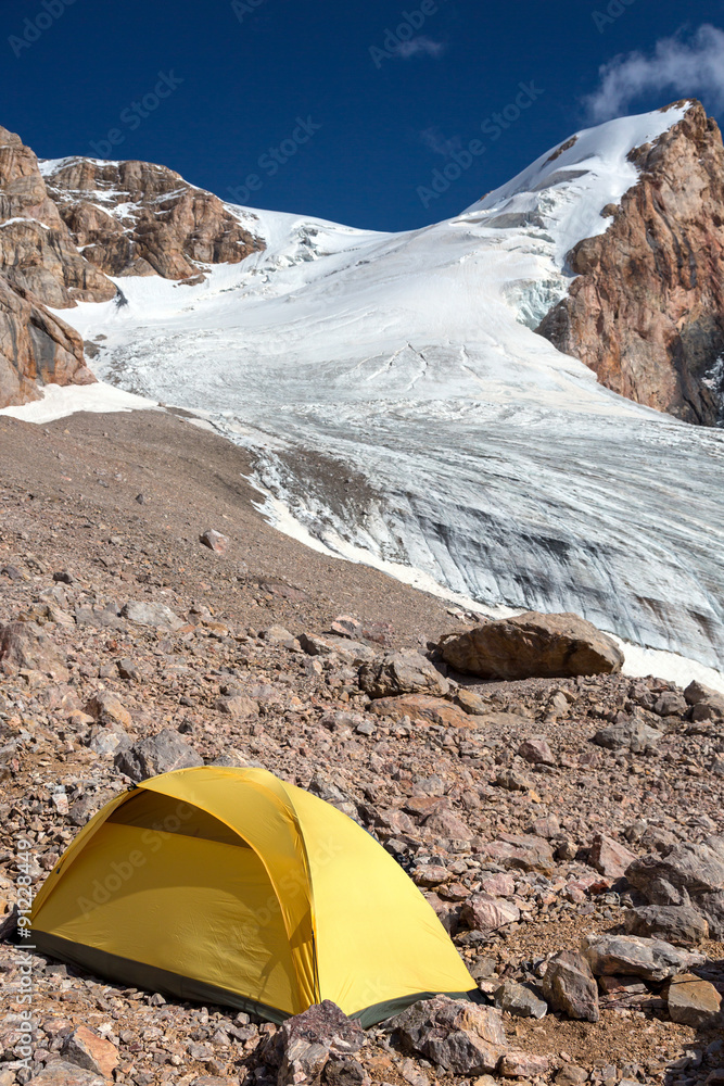 Glacier Flow and Yellow Tent
Mountain View with Ice Glacier and Peaks on Background and Small Single Alpine Yellow Tent located on Rocky Moraine on Foreground