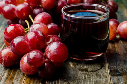 Red grape and juice on wooden background