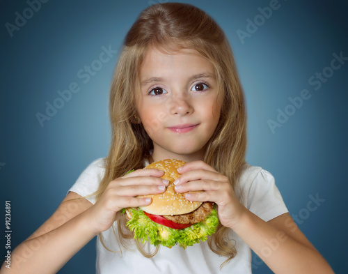 Child girl holding hamburger. Kid with fastfood sandwich.