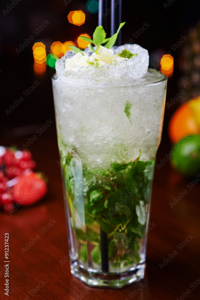 bright mojito cocktail on a table in the restaurant with the decor of ice and apple slices with bright backgrounds of beautiful disco lights. soft focus bright mojito cocktail on a table in the restaurant with the decor of ice and apple slices with bright backgrounds of beautiful disco lights. soft focus