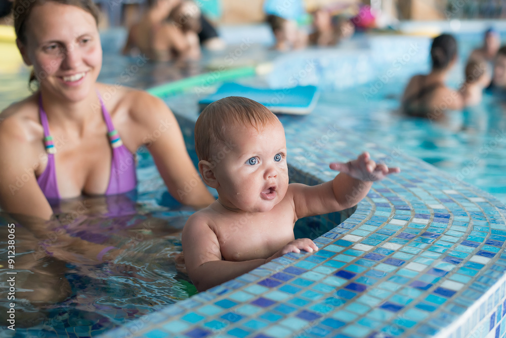 Obraz premium Young family with baby having fun in the swimming pool.