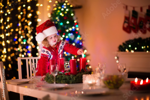 Child lighting a candle at Christmas dinner