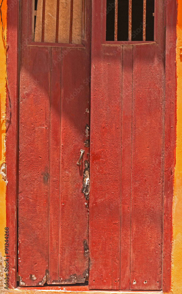 Cherry coloured stained ancient door with bars on windows,open Cherry coloured stained ancient door with bars on windows,open