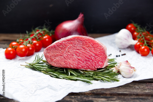 a pieces of fresh meat, beef slab, decorated with greens and vegetables. photo