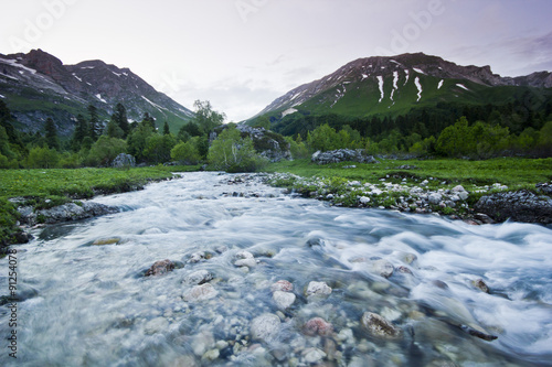 blue mountain river surrounded by high peaks at sunset