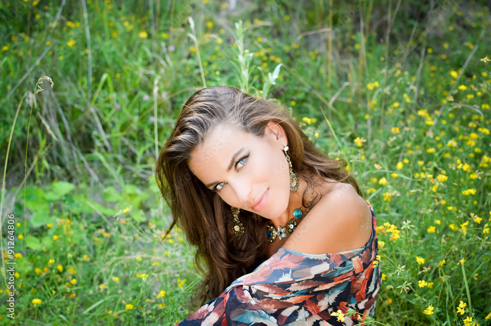 Beautiful girl in fancy earrings and necklace smiling on meadow Beautiful girl in fancy earrings and necklace smiling on meadow