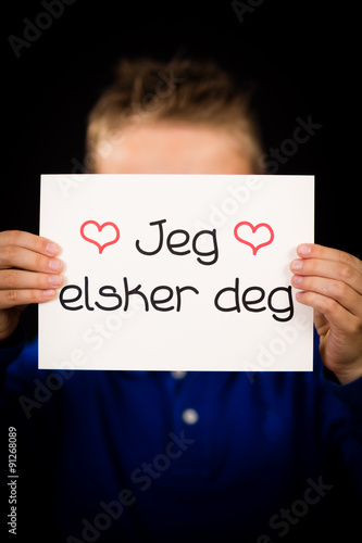 Child holding sign with Norwegian words Jeg Elsker Dig - I Love