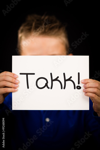 Child holding sign with Norwegian word Takk - Thank You