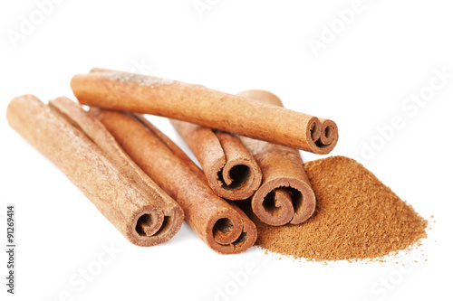 Closeup of cinnamon sticks and powder of ground cinnamon on white background