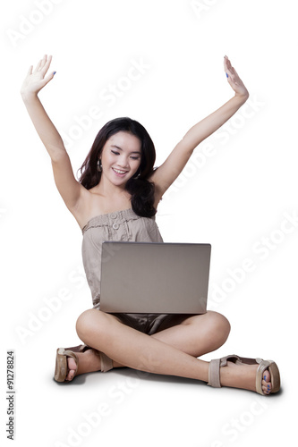 Cheerful girl using laptop and raise hands © Creativa Images