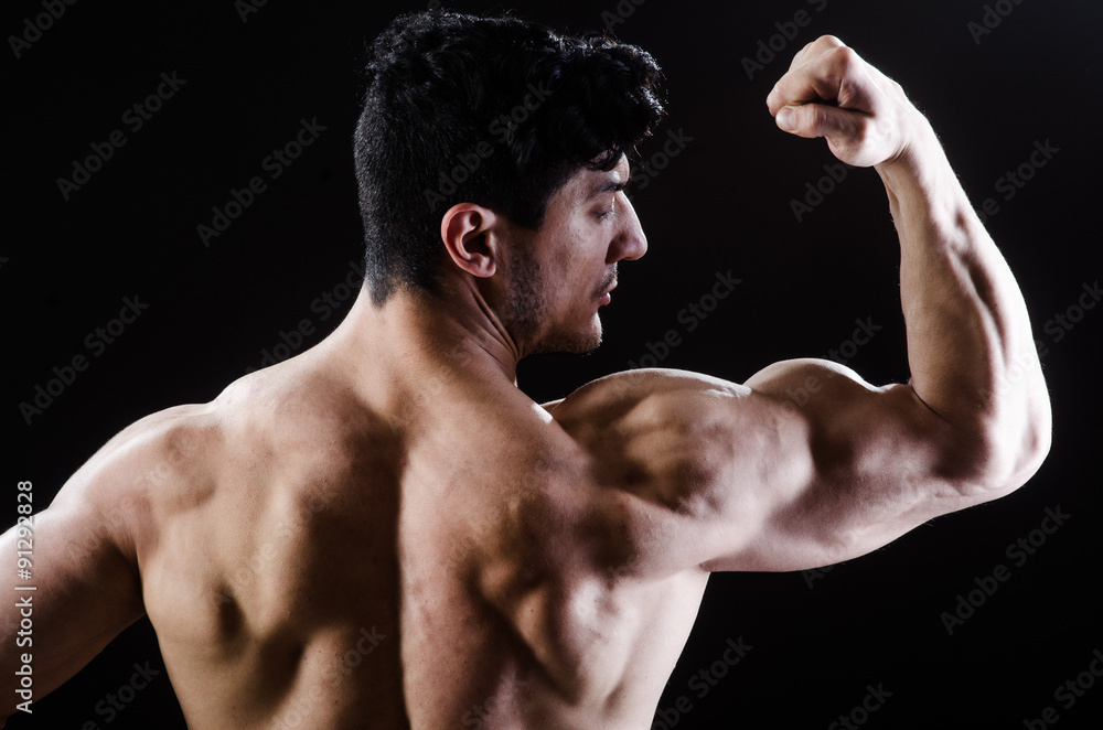 Muscular man posing in dark studio